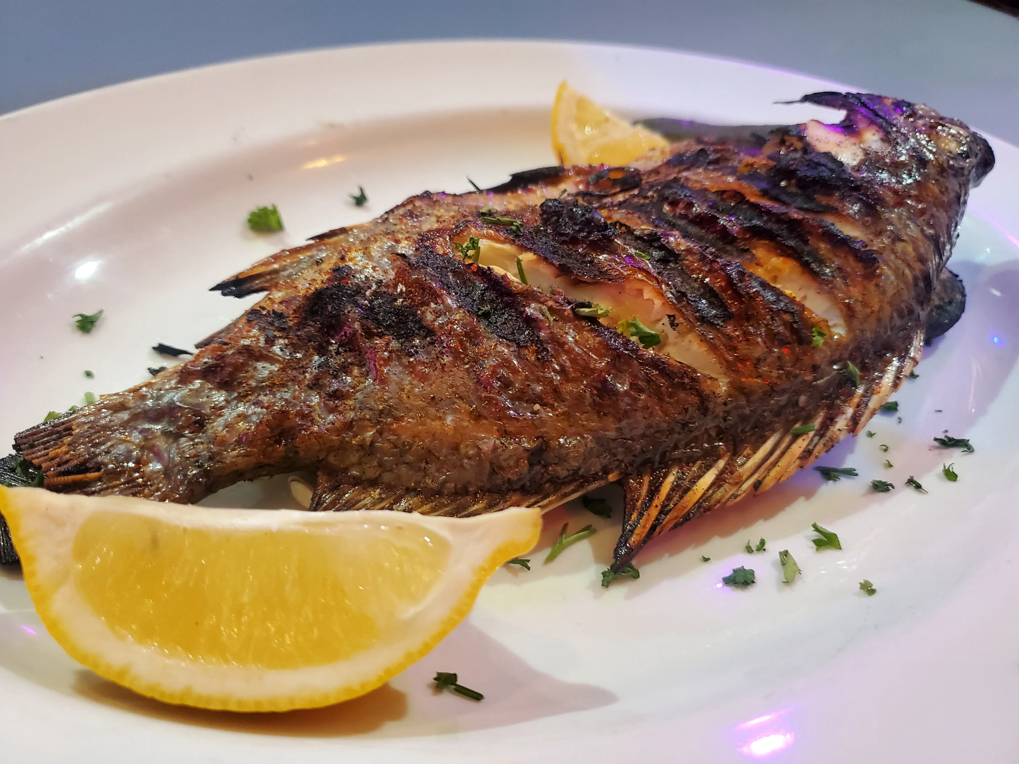 Whole grilled fish served with lemon